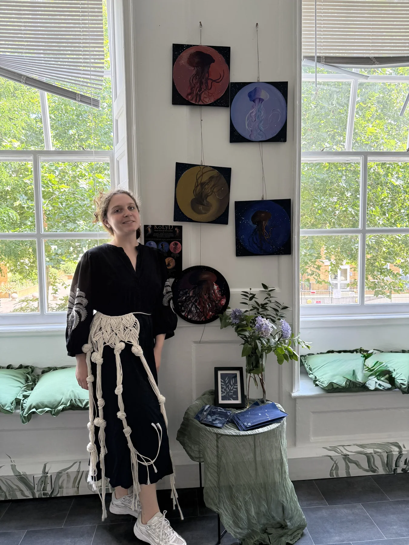 Diana Kobrosli-Lytvynchuk standing beside her cosmic jellyfish artworks.